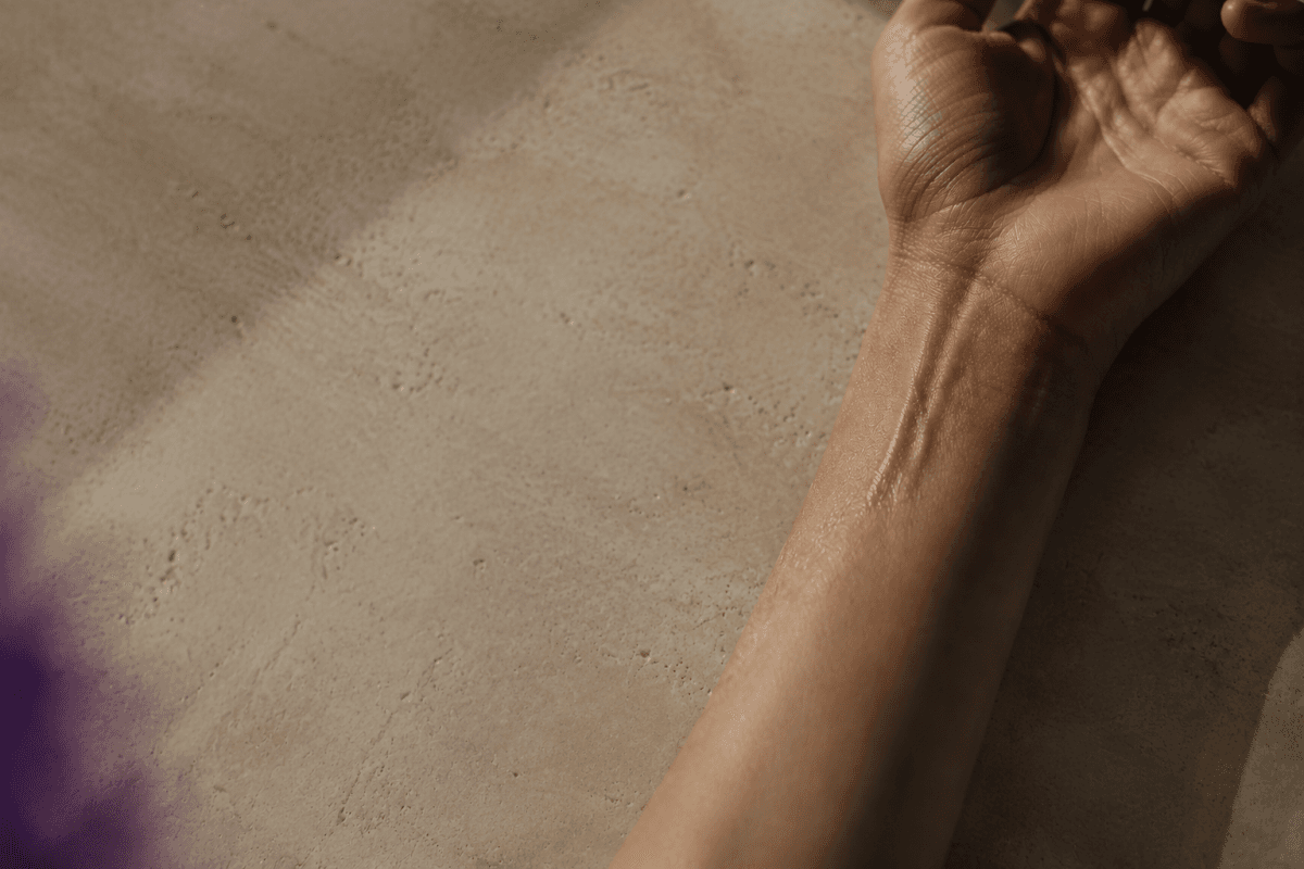An AURĒ extrait de parfum bottle on a warm neutral surface in natural light